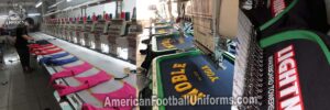 High-speed embroidery machine at American Football Uniforms applying custom tackle twill numbering to a team football jersey.